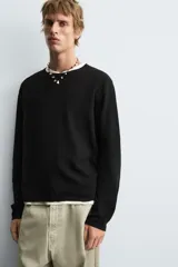 Jersey de manga larga, cuello redondo y calce relajado, color negro con efecto lavado y textura tejida.
