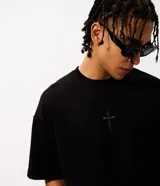 Remera oversize de tejido tipo gamuza sintética negra, con cuello redondo, manga corta y bordado de cruz gótica en el pecho.