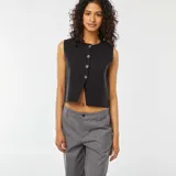 Chaleco negro de punto fino, sin mangas, con cuello redondo y cierre frontal de botones.