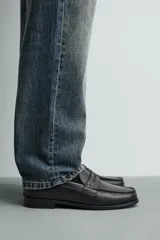 Mocasín de cuero negro con antifaz en el empeine y suela a tono con ligero tacón.