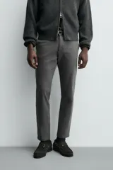 Pantalón chino de corte ajustado, color beige, con bolsillos laterales y bolsillos traseros de vivo. Cuenta con cierre frontal de cremallera y botón.