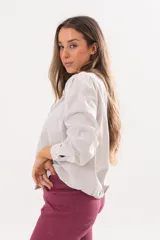 Camisa beige a rayas finas de manga larga, con cuello camisero y cierre frontal oculto.