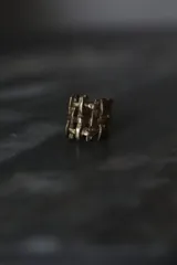 Anillo de diseño abierto con estructura de rejilla entrelazada, elaborado artesanalmente en metal con acabado plateado.