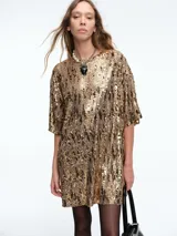 Vestido corto de corte recto y holgado, confeccionado en tejido cubierto de lentejuelas doradas. Presenta cuello redondo, mangas cortas amplias y una caída fluida.