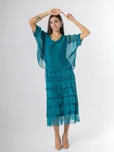 Vestido midi de seda italiana color negro, diseño dos en uno con capa superior de calce amplio, falda con volados y forro interior de algodón elastizado.