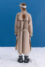 Trench midi color camel, confeccionado en mezcla de algodón y nylon. Presenta cuello clásico, cierre frontal con botones, tajos laterales y bolsillos internos. Es una prenda repelente al agua con diseño versátil y funcional.