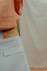 Pantalón de corte ancho y silueta abombada, color gris claro, con bolsillos frontales y costuras decorativas verticales.