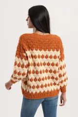 Cardigan de punto con diseño geométrico de rombos en colores naranja y crema. Presenta escote en V, cierre frontal con botones y puños y ruedo acanalados.
