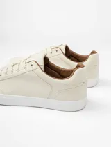 Championes urbanos de diseño minimalista en color beige, con suela de goma blanca y detalles en color marrón en el interior y borde del cuello.