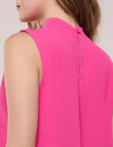 Blusa sin mangas color verde, confeccionada en crepé texturizado, con cuello alto drapeado y torsión central frontal.