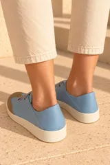 Championes de cuero vacuno color celeste con puntera de gamuza marrón, suela de goma y cordones elásticos.