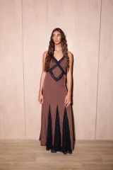 Vestido largo de seda color marrón con estampado de lunares blancos y detalles de encaje negro. Presenta un diseño entallado en el torso, escote en V profundo y espalda descubierta con tiras cruzadas.