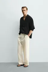 Camisa tipo kimono de corte relaxed fit, color celeste, confeccionada en tejido fluido de viscosa y lino. Presenta cuello con solapas de muesca, manga corta y cierre frontal cruzado con doble botonadura.