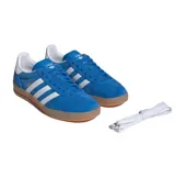 Championes Adidas Gazelle Indoor de gamuza azul con las icónicas tres rayas laterales en blanco. Presenta una suela de caucho color caramelo, talón blanco y detalles dorados con el nombre del modelo en el lateral.