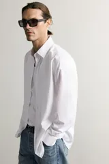 Camisa slim fit de Zara confeccionada en tejido de algodón con textura estructurada, cuello clásico con solapa y manga larga con puños abotonados. Cierre frontal con botonadura.