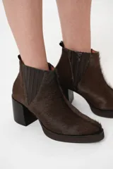 Bota de cuero con pelo color chocolate, de caña corta con taco bloque de 8 cm y plataforma de 2 cm. Presenta elástico forrado en el lateral y cierre en el lado interno para facilitar el calce.