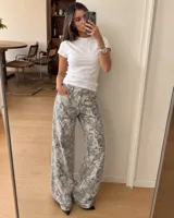 Pantalón de jean de corte recto y tiro medio, con estampado tipo camuflado de ramas en tonos grises y blancos.