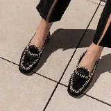 Mocasín negro de cuero vacuno con horma cuadrada, tientos de cuero pasados a mano y suela de goma.