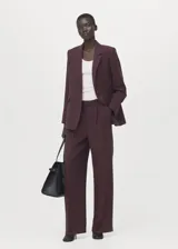 Blazer de diseño recto estilo traje, color bordó, confeccionado en tejido de lyocell. Cuenta con cuello pico con solapa de muesca, manga larga con puños abotonados, dos bolsillos laterales con solapa y cierre frontal de un botón.