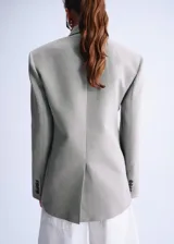 Blazer cruzado de lino y algodón color verde militar, con cuello solapa, hombreras marcadas, bolsillos con solapa y cierre de doble botonadura.