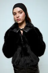 Chaqueta de pelo sintético color negro, con cierre frontal y bolsillos laterales.