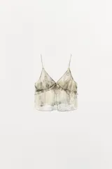 Top lencero de viscosa con estampado sutil, escote en pico y tirantes finos. Presenta detalle de volantes horizontales y lazada frontal en el pecho.