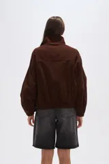 Campera corta marrón de pana, con cuello alto, cierre frontal con broches a presión, bolsillos plaqué con solapa y puños elásticos.