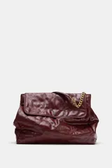 Bolso tipo shopper color borravino con diseño acolchado y pespuntes en rombos. Cuenta con solapa frontal y una correa de hombro que combina material sintético con una cadena metálica dorada.