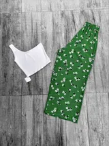 Pantalón tipo palazzo de corte recto y holgado, con cintura elástica y estampado floral blanco sobre fondo verde.