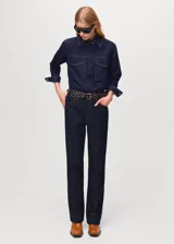 Camisa de jean de algodón con cuello camisero, cierre frontal de botones ocultos, mangas largas con puños abotonados y dos bolsillos delanteros con solapa.