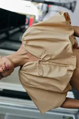 Cuerpo corto de cuello redondo con frunces, escote en pico con lazada y mangas cortas abullonadas con elástico interior.