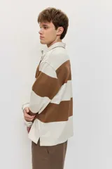 Chomba de friza de manga larga con diseño de rayas horizontales anchas en color beige y azul, cuello polo y pequeño bordado en el pecho.