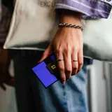 Billetera tarjetero Baleine Card Slider de aluminio color violeta, con mecanismo deslizante y logo de la marca estampado en el frente.
