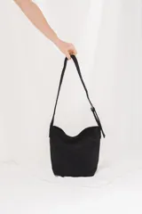 Cartera tipo morral y bandolera de gamuza marrón, con correa larga ajustable y diseño estilo hobo.