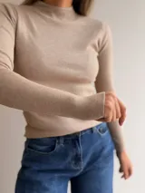 Media polera de tejido fino y ajuste al cuerpo, con cuello alto y mangas largas. Confeccionada en una mezcla de viscosa, poliéster y nailon, ofrece un diseño versátil y elegante para uso diario.