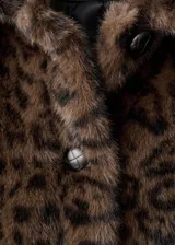 Abrigo de efecto pelo con diseño de estampado de leopardo, cuello camisero, corte oversize y cierre frontal con botones.