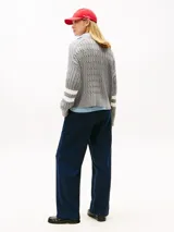 Sweater gris de tejido trenzado con cuello redondo y manga larga, confeccionado en algodón orgánico. Presenta un logo script TH gráfico bordado en color blanco en el centro del pecho.