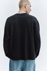 Remera de manga larga en punto pesado, con cuello redondo, hombros caídos y corte oversized.