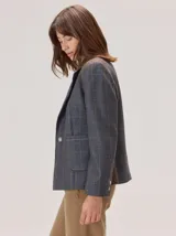 Blazer de denim estructurado con solapas clásicas, cierre frontal de un botón y bolsillos laterales con solapa. Presenta costuras visibles en contraste y un corte sastrero.