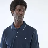 Remera polo de piqué color azul marino con detalles blancos en el cuello y los puños, cierre frontal con botones y pequeño logo bordado en el pecho.