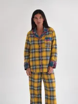 Pijama largo de franela a cuadros en tonos amarillo, azul y verde, compuesto por una camisa de manga larga con botones y ribetes fucsias, y un pantalón recto holgado.