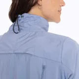 Campera técnica de mujer con cuello alto y cierre frontal completo. Presenta un diseño híbrido con panel frontal acolchado con patrón de espiga y mangas y espalda en tejido liso. Incluye bolsillos laterales y elástico ajustable en la cintura.