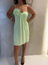 Vestido corto de color verde menta, con breteles finos, detalle de flor aplicada en el hombro y drapeado frontal en el escote.