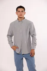 Camisa de manga larga en color gris, confeccionada en algodón, con cuello abotonado y cierre frontal de botones.