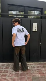 Remera blanca de algodón con estampado negro en la espalda que incluye el logo de la marca, una estrella y texto.