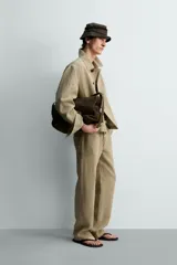 Sobrecamisa cropped fit de lino color beige, con cuello solapa, mangas largas con puño abotonado, bolsillos frontales de vivo y cierre frontal con botones oscuros.
