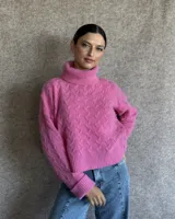 Sweater de lana color crudo con cuello alto y diseño trenzado.