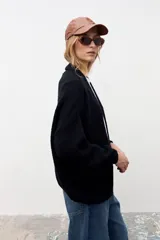 Cardigan de punto color negro, con diseño abierto sin botones, mangas largas con puños ajustados y corte holgado.