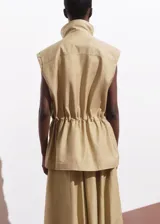 Chaleco oversize color beige, sin mangas, con cuello de solapa, cuatro bolsillos de parche con solapa en la parte delantera, fruncido elástico en la cintura y cierre frontal con botones.