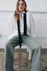 Camisa oversize de algodón con cuello redondo y solapa, manga larga con puño con vuelta y hombro caído. Presenta detalle de tablas en el delantero, cierre frontal con botones ocultos y corbata a contraste incluida.